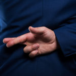 Closeup view of dishonest businessman standing with crossed fingers