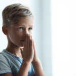 little boy praying with hands clasped