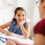 Hispanic Mother Helping Girl Doing School Homework At Home