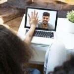 Child video chatting over a laptop with her father