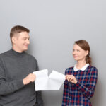 Studio shot of adult couple holding and tearing paper sheet