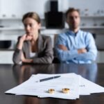 selective focus of couple sitting at table with divorce documents