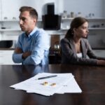 selective focus of couple sitting at table with divorce documents