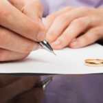 Closeup of male hand signing divorce papers