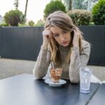 Portrait of depressed teenage girl sitting in coffee shop.