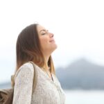 Happy woman on the beach breathing fresh air