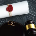 Two broken golden wedding rings divorce decree document. Divorce and separation concept