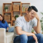 Sorrowful man covering eyes after conflict with woman