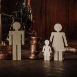 Wooden figures of family with child and gavel on a table. Divorce and alimony concept