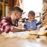 happy father and son with blueprint at workshop