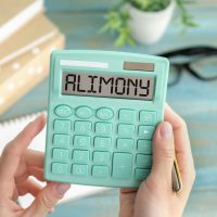 Word ALIMONY written on calculator on office table.